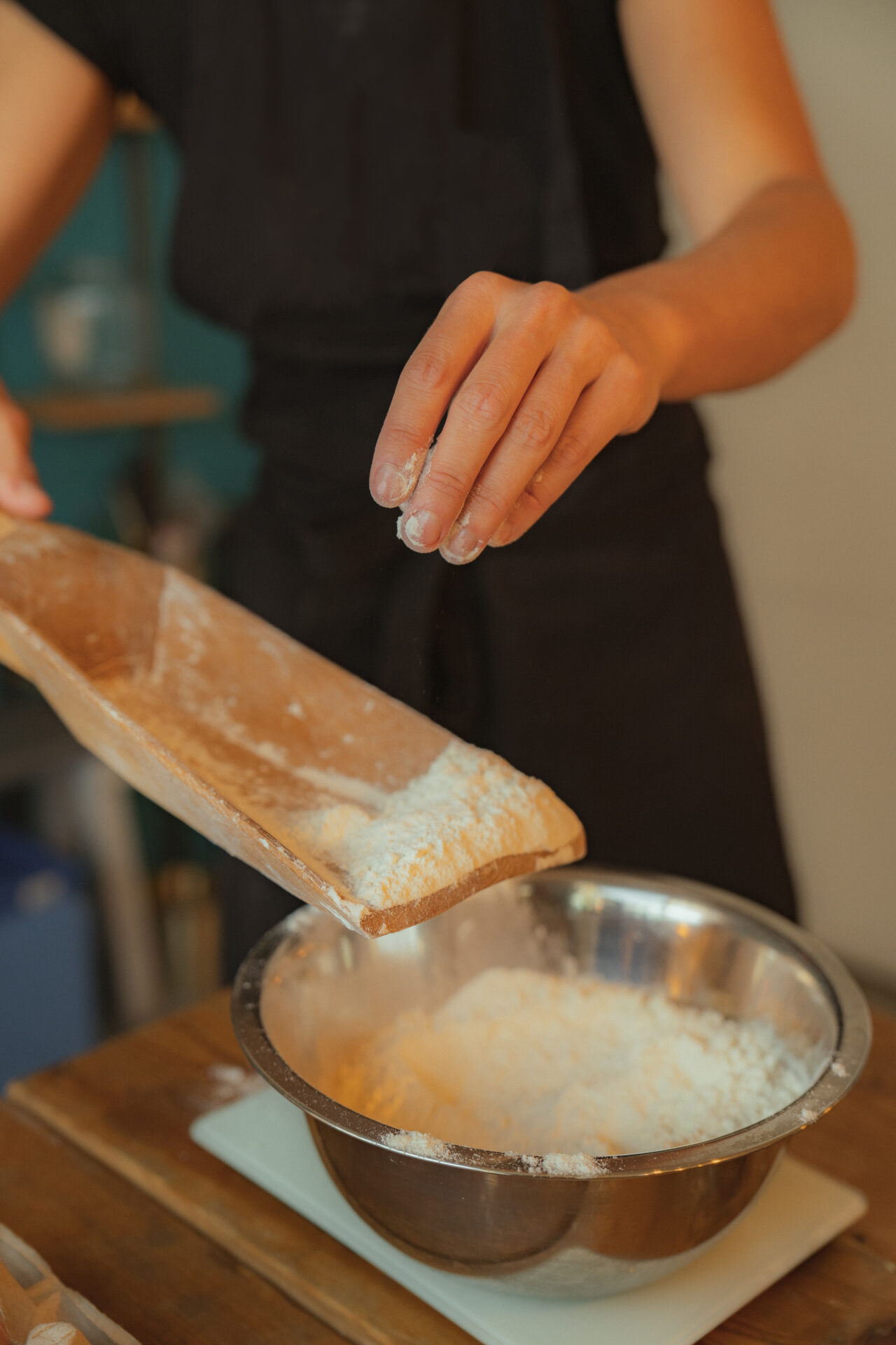la farine de Flietermolen est ajoutée à la préparation des cookies Charlie de Coeur de beurre Bruxelles avec une grande pelle en bois traditionnelle