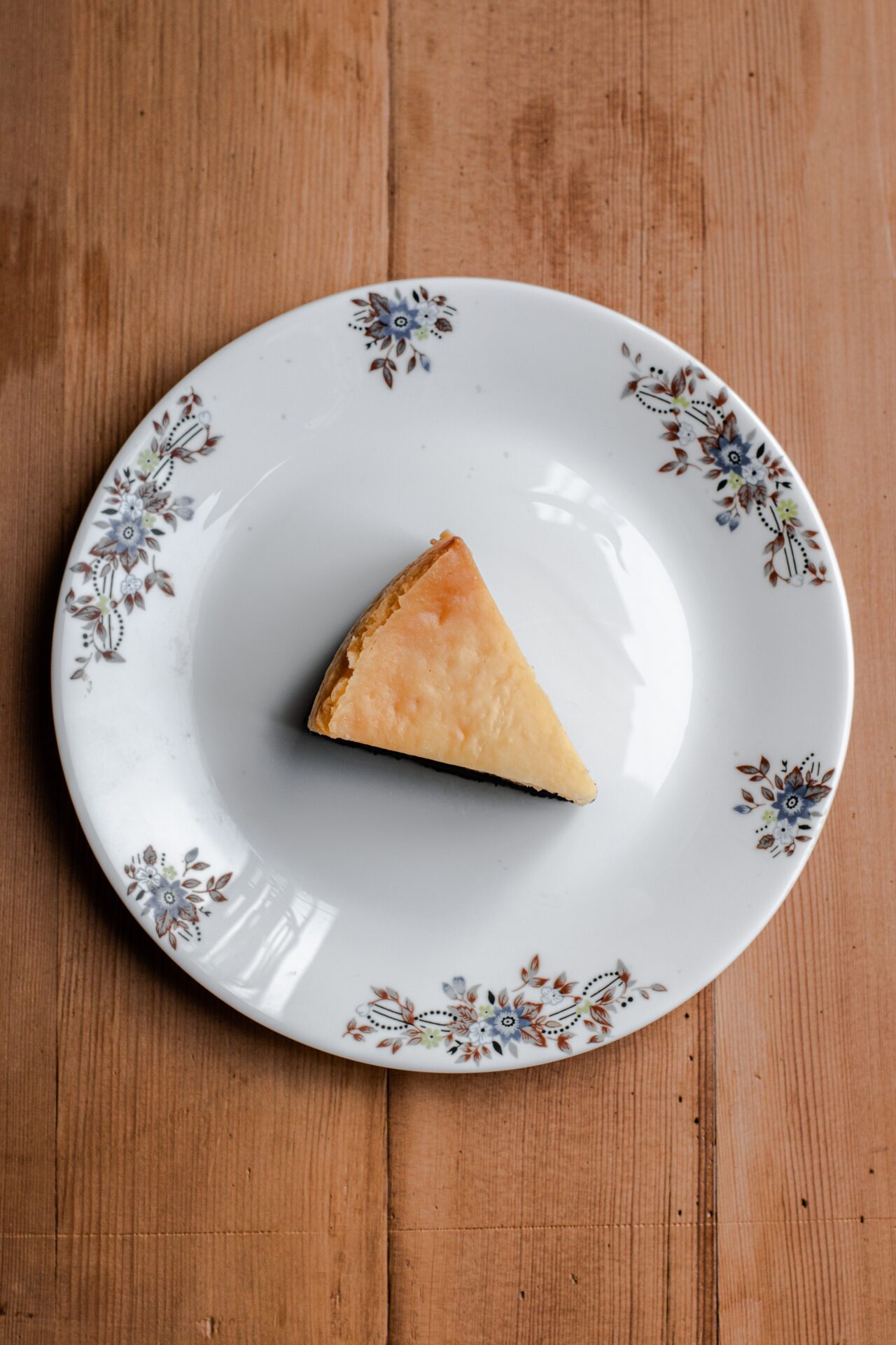recette anti gaspi part de cheesecake au cookies coeur de beurre sur une assiette en porcelaine et une table en bois, par @abhishek_hajare